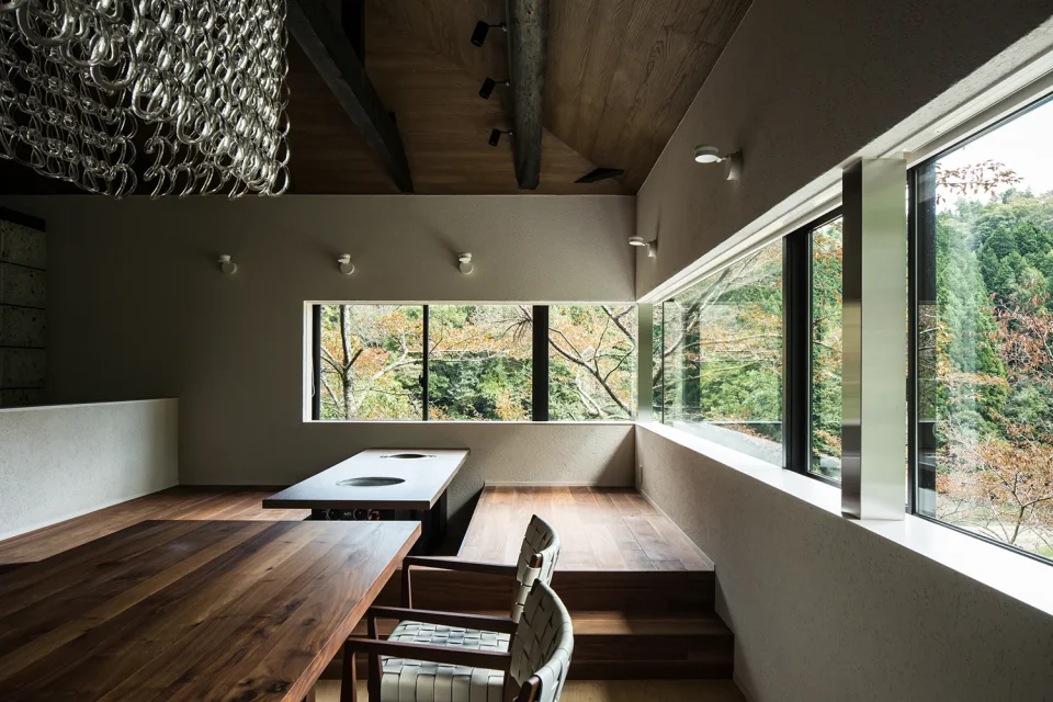 亀岡のVILLA／保養所リノベーション2。二方向に続く横長の窓から木々を眺めるダイニング